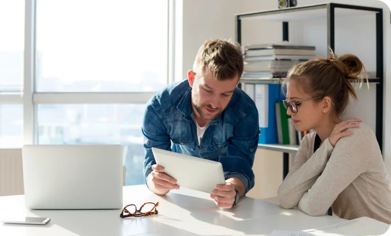 Coworkers reviewing tablet in bright office