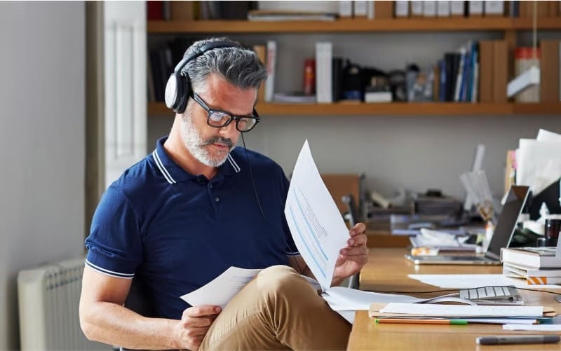man sitting at a desk reading papers with headphones on