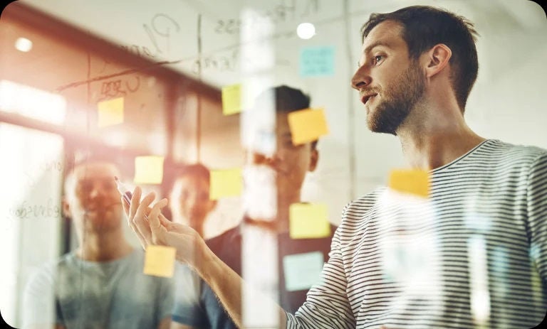 Team brainstorming with sticky notes on glass